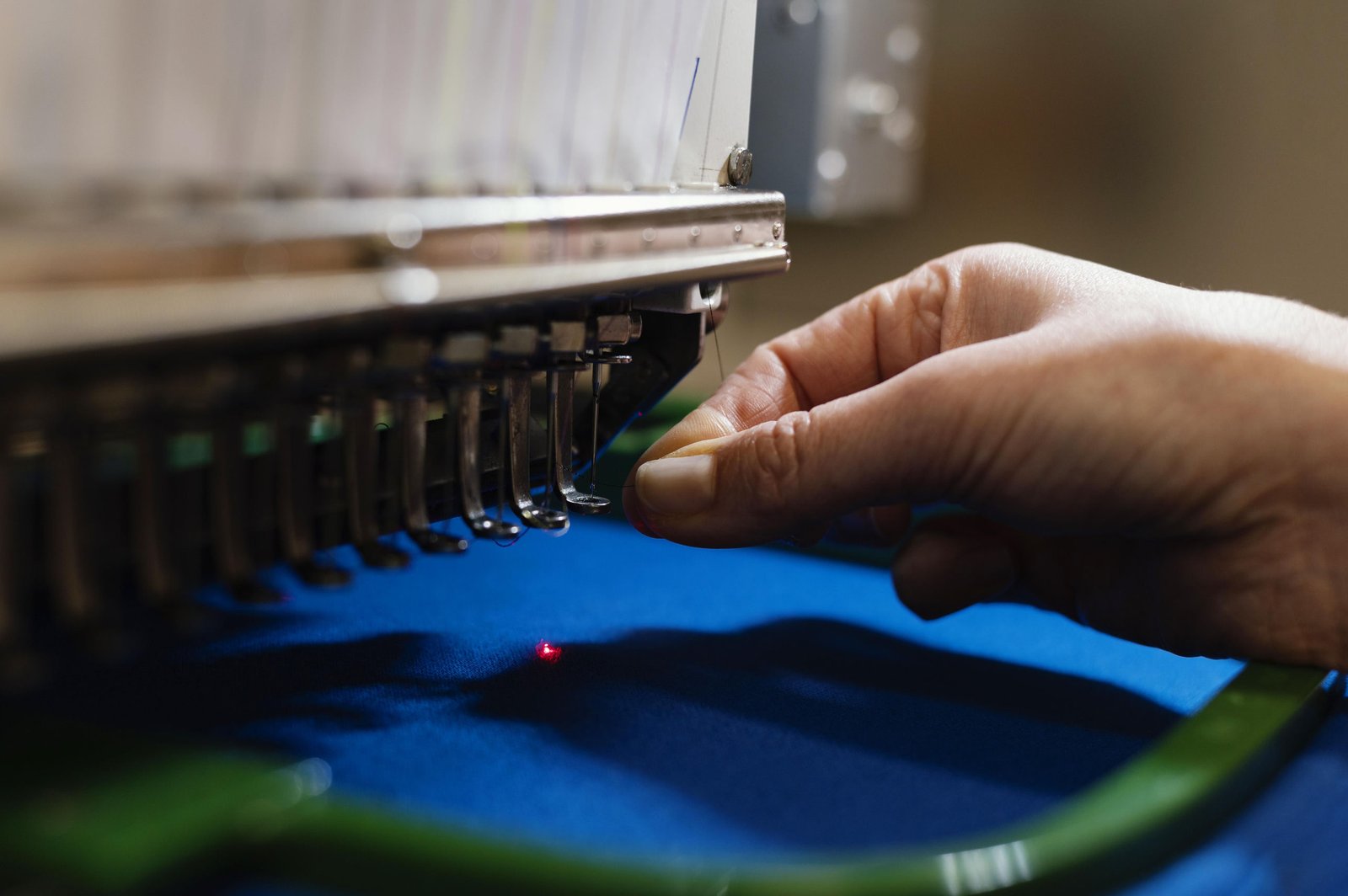 Brodeuse industrielle en action — aiguille sur textile bleu