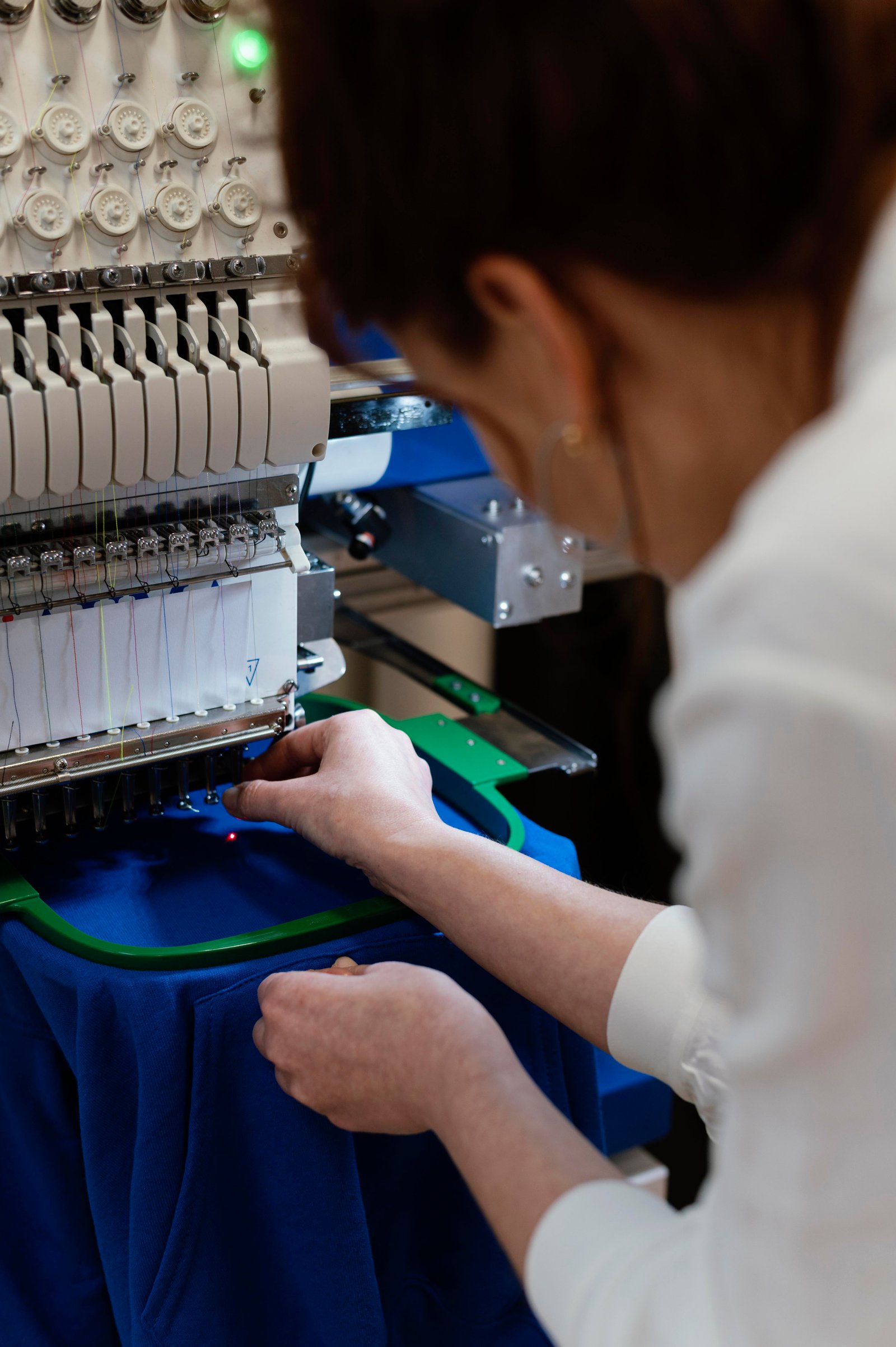 Broderie textile détail — fil couleur en relief sur polaire, atelier NVNC Valais